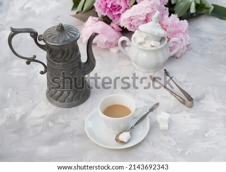 vintage still life with a cup of coffee against a bouquet of pink peonies 