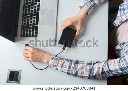 holding backup external hdd with archive and connect it to the laptop Royalty-Free Stock Photo #2143703841