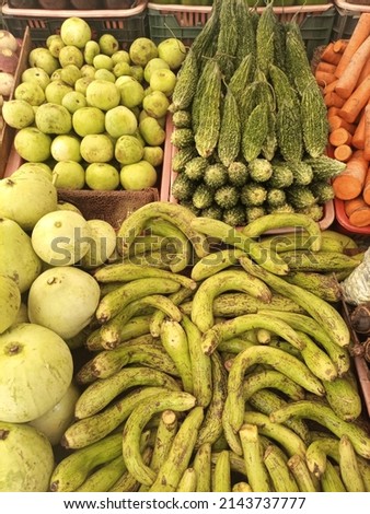 A stall fill with assorted gourds (bitter, snake , round , bottle ) with carrots  