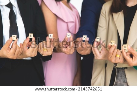 Studio shot of small wooden cube block thank you letters alphabets  holding by unrecognizable unidentified faceless female officer staff in business wears show appreciation to customers colleagues.