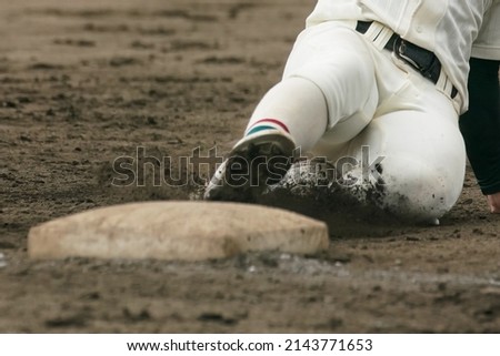 Baseball player sliding into a base while attempting to steal a base during a baseball game.