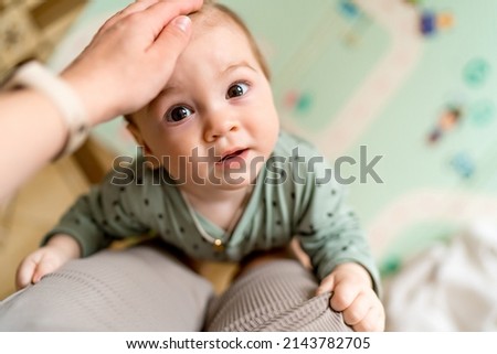 Top view of portrait of a baby boy, embracing mothers leg. A 9 month old baby lifting up on the mothers leg. High quality photo Royalty-Free Stock Photo #2143782705