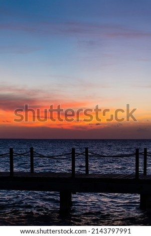 Rope bridge silhouette at sunset. Beautiful seascape, bright orange sky and sea. High quality photo