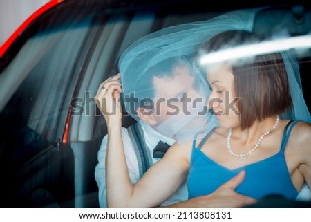 Portrait of a young couple in wedding attire celebrating their wedding anniversary. The couple is washing the car. Smile, kiss, love.