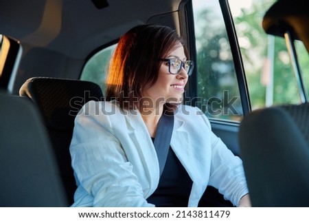 Portrait of business elegant middle-aged woman in car in back passenger seat Royalty-Free Stock Photo #2143811479