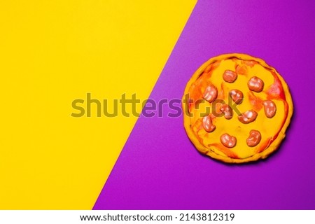 model of pizza from plasticine on a two-tone background with copy space