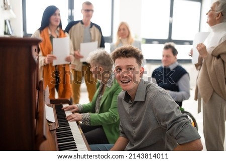 Group of seniors with young teacher singing together at choir rehearsal. Royalty-Free Stock Photo #2143814011