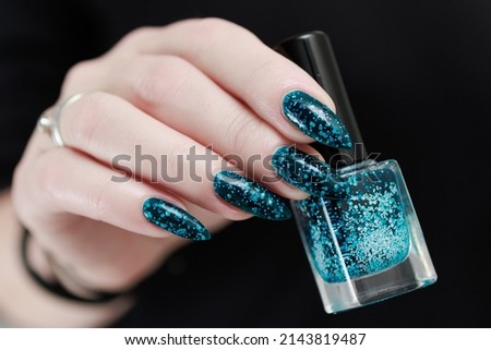 Woman hand with long nails and teal blue green nail polish