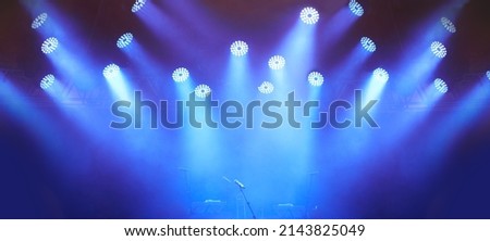 An empty stage - evoking anticipation. A stage at a music festival with lights streaming down from above. Royalty-Free Stock Photo #2143825049
