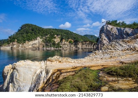 Ancient volcanic rock sea cliffs covered with Japanese pine forests under a blue sky on a famous volcanic island in the Japan Sea. Royalty-Free Stock Photo #2143829773