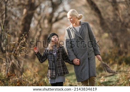 Beautiful mother with her daughter in the spring park. A young woman with a girl walk in the forest in spring. Motherhood. Brown.