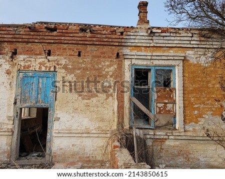 Destroyed rural house with broken windows and doors. Abandoned home with shabby paint