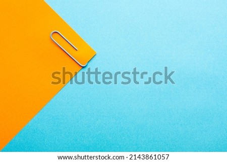 Minimalist background with blue paper clip on colorful background with free copy paste space for text.