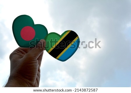 Hand holds a heart Shape Bangladesh and Tanzania flag, love between two countries