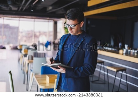 Young freelancer man working in a cafe with a notepad, a businessman with a notepad, a man in a jacket and glasses