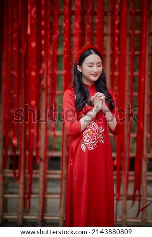 Ho Chi Minh City, Vietnam: Portrait of a brilliant Vietnamese girl in a red ao dai to welcome the Vietnamese traditional New Year Royalty-Free Stock Photo #2143880809