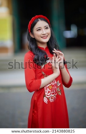 Ho Chi Minh City, Vietnam: Portrait of a brilliant Vietnamese girl in a red ao dai to welcome the Vietnamese traditional New Year Royalty-Free Stock Photo #2143880825