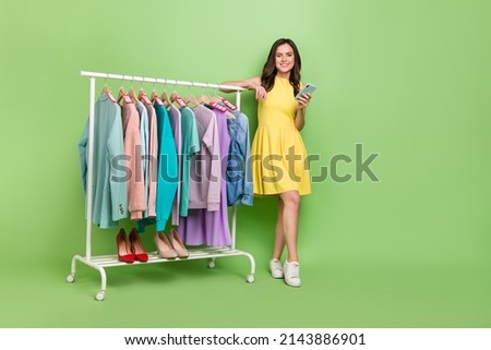 Full size photo of pretty cheerful person hold telephone store rack isolated on green color background
