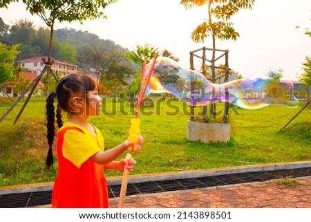 Lovely Baby girl wears yellow-orange outfit, gokowa outfit or Mugunghwa playing bubble in a public park. Girls and teen fashion dress.