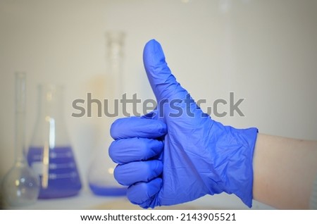 Hand in blue glove showing thumbs up gesture