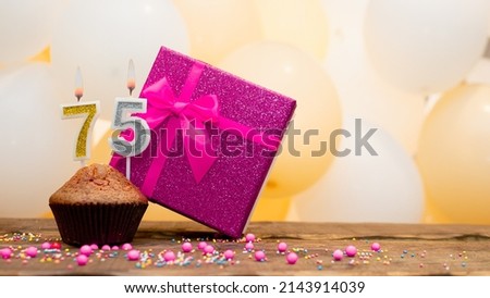 Happy birthday with pink gift box for 75 year old woman. Beautiful birthday card with cupcake and burning candle number seventy five