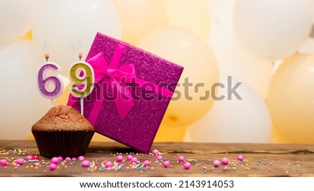 Happy birthday with a pink gift box for a 69 year old woman. Beautiful birthday card with cupcake and burning candle number sixty nine