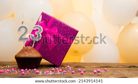 Happy birthday with a pink gift box for a 23 year old girl. Beautiful birthday card with a cupcake and a burning candle number twenty three