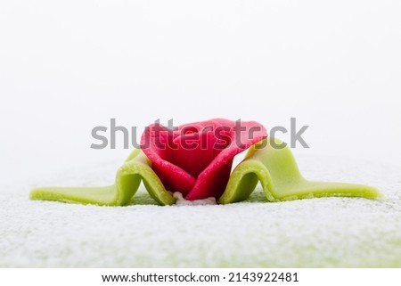 close up picture of a red marzipan rose on a princess cake 