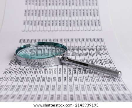 Spreadsheet, table with magnifying glass. Scrutinizing numbers. Statistic, analytic data analysis and audit. Business and finance concept. Information search. High quality photo