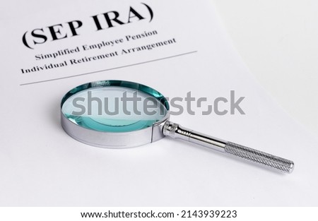 Paper with SEP IRA words and magnifying glass. Simplified Employee Pension Individual Retirement Arrangement. Analysis and planning of contributions. Business and finance concept. High quality photo