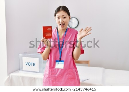 Young asian nurse woman at political campaign election holding swiss passport celebrating achievement with happy smile and winner expression with raised hand 