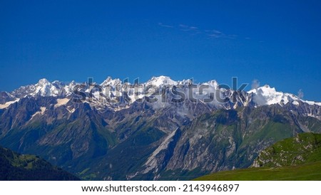 Scenic view of a green grassy hill, a mountain flower meadow and the snowy peaks of the Alps in Verbier, Switzerland. Place for photo Panorama of wooden letters. Cyclists. parachuting. Green Planet