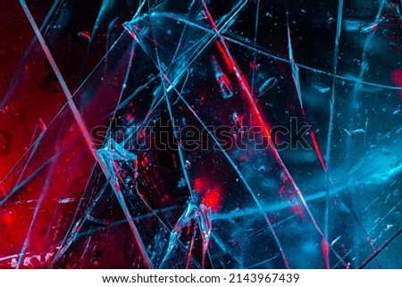 Close-up photo texture of blue and red toned broken and cracked glass on black backdrop. Royalty-Free Stock Photo #2143967439