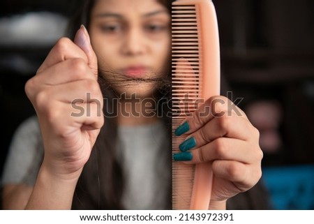 Young Indian woman getting worried about her hair fall problems.