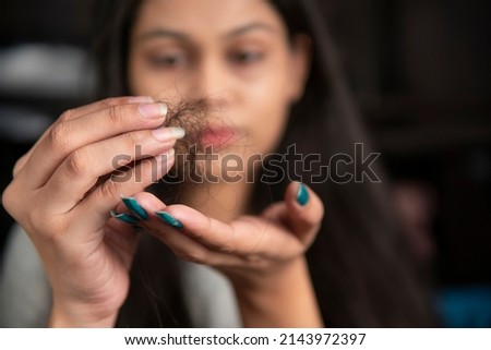 Young Indian woman getting worried about her hair fall problems. Royalty-Free Stock Photo #2143972397
