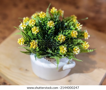 Green decorative artificial flower with yellow flowers .