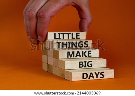 Little things make big days symbol. Wooden blocks with words Little things make big days. Beautiful orange background, copy space. Businessman hand. Business, motivational concept.
