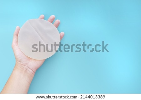 Top view silicone implants breast augmentation on space blue or turquoise background, Gel type and rough touch surface in hand, Medical equipment used in clinic or hospital.