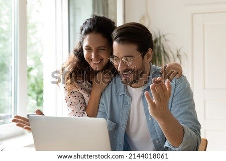 Surprised happy cheerful 35s couple read great unbelievable amazing news on laptop, e-commerce cheery clients, online lottery winners celebrate victory, low price and special commercial offer concept Royalty-Free Stock Photo #2144018061