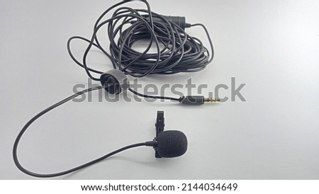 long cable clip-on mic isolated on white background. Small lavalier microphone with clip. Professional sound recording equipment. Lapel mic.
