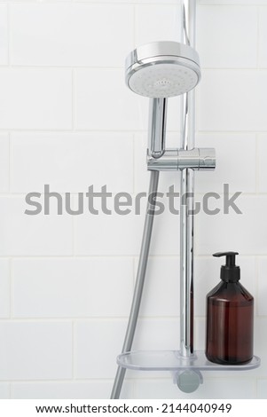 Shower rack with hanging shower head and shelf with bottle of gel. Royalty-Free Stock Photo #2144040949