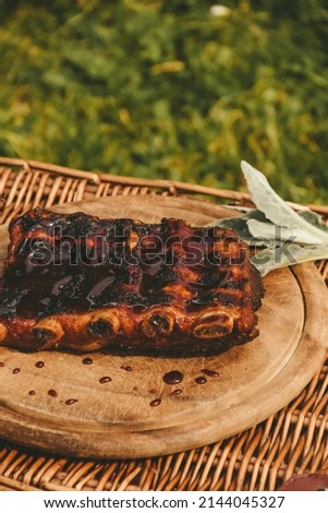 Grilled pork ribs with a sweet and sour sauce on a wooden board. Barbecue. Picnic.