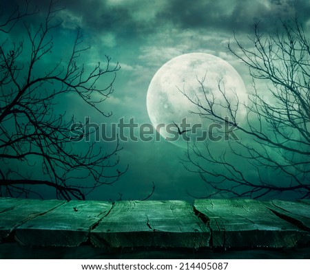 Halloween background. Spooky forest with full moon and wooden table Royalty-Free Stock Photo #214405087