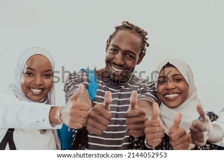 Group portrait of happy African students standing together against a white background and showing ok sign thumbs up girls wearing traditional Sudan Muslim hijab fashion