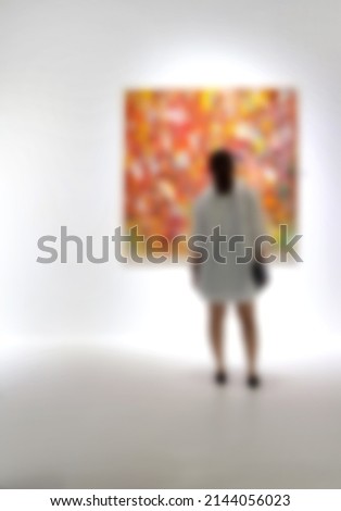 People looking at paintings on white wall in Art exhibition gallery. Blurry background.