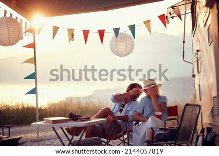 Couple in love. Sitting in front of camper rv. Having fun. Outdoors summer party. Fun, togetherness, nature concept. Royalty-Free Stock Photo #2144057819