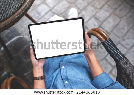Top view mockup image of a woman holding digital tablet with blank white desktop screen in the outdoors cafe