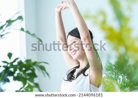 A woman taking a deep breath while bathing in the light by the window Royalty-Free Stock Photo #2144096181