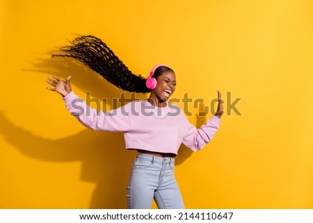 Photo of overjoyed carefree girl listen song mp3 raise hands scream isolated on yellow color background