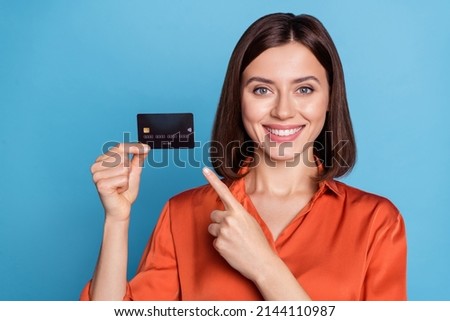 Portrait of attractive cheerful girl holding in hand demonstrating bank card isolated over bright blue color background
